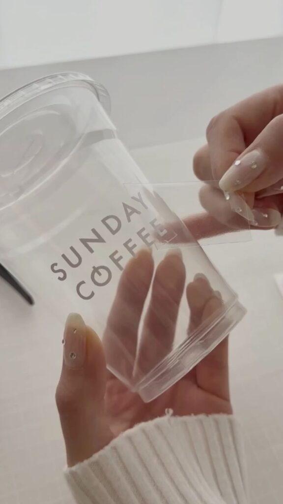 CAMEO5で作ったカッティングフィルムのラベルを透明カップに貼っている様子