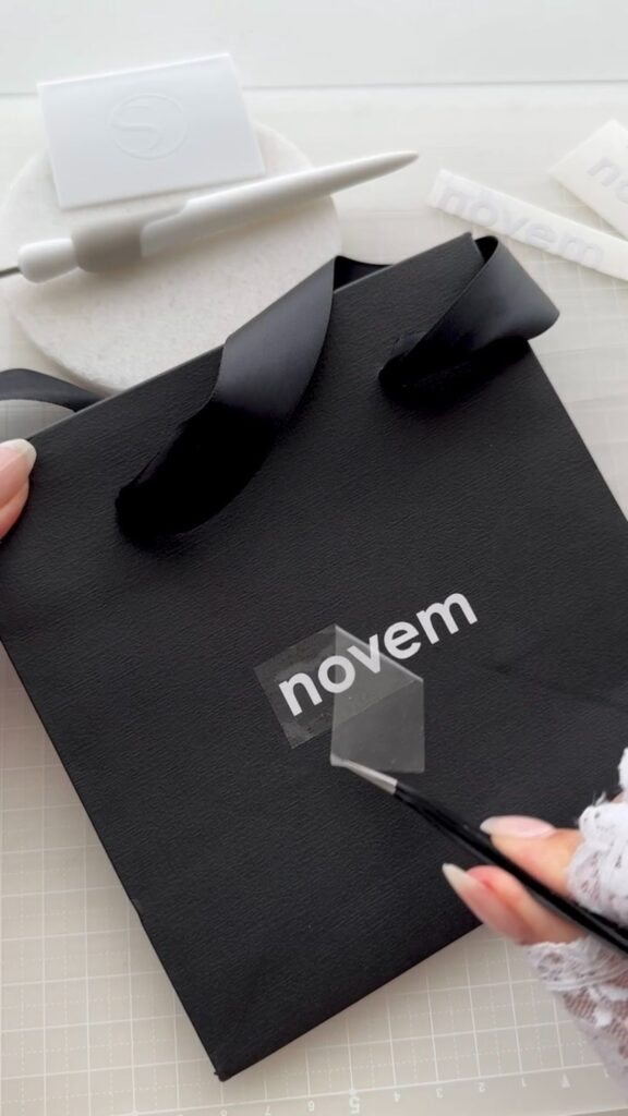 カッティングフィルムのロゴを紙袋に貼り付けている様子