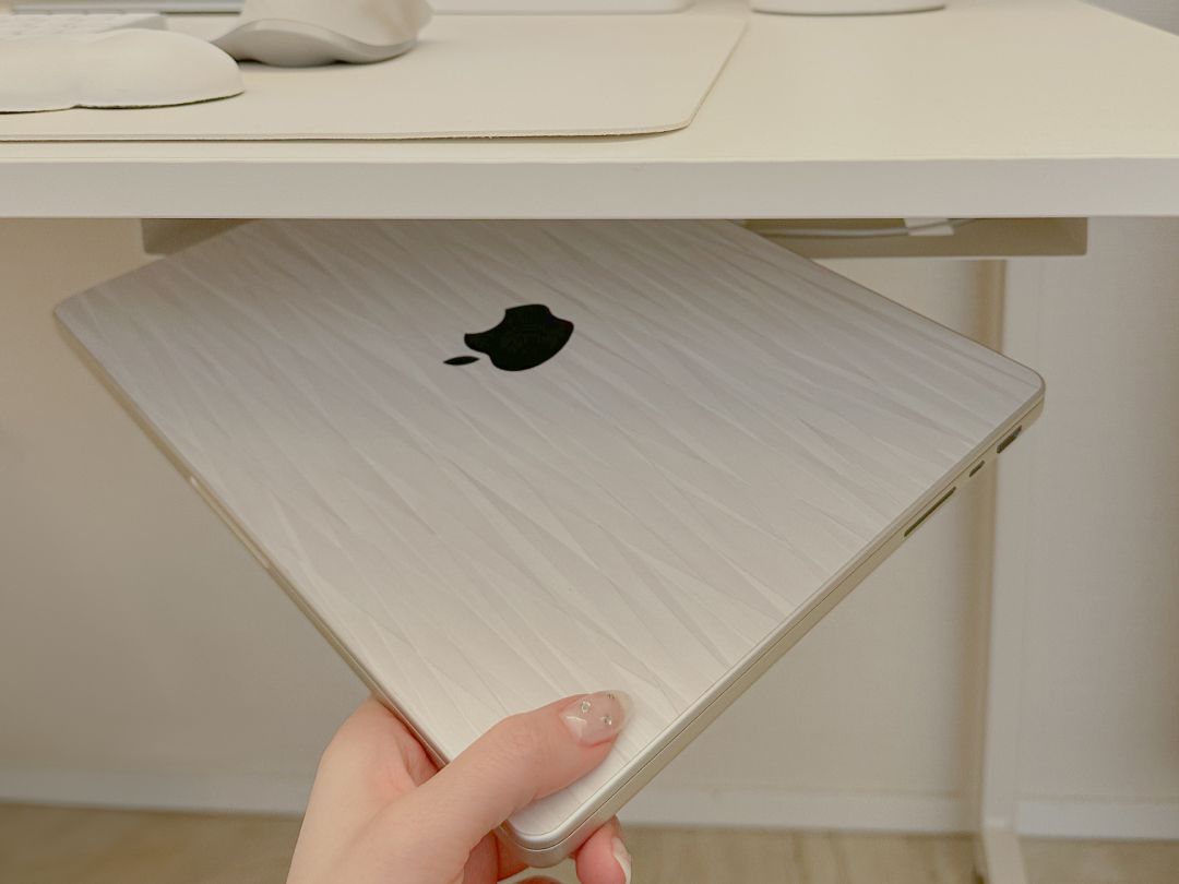 sp-fullwide-image 白いスキンを貼ったMacBook Proをデスク環境で手に持っている様子